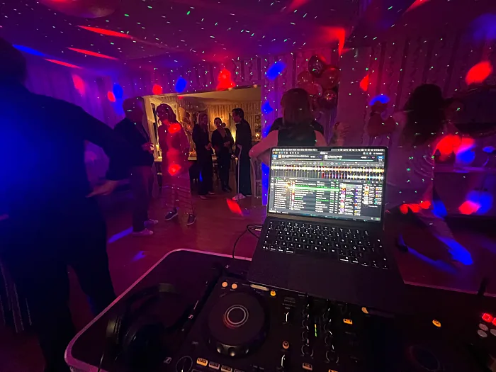 DJ-bord och laptop i ett rum med färgat ljus